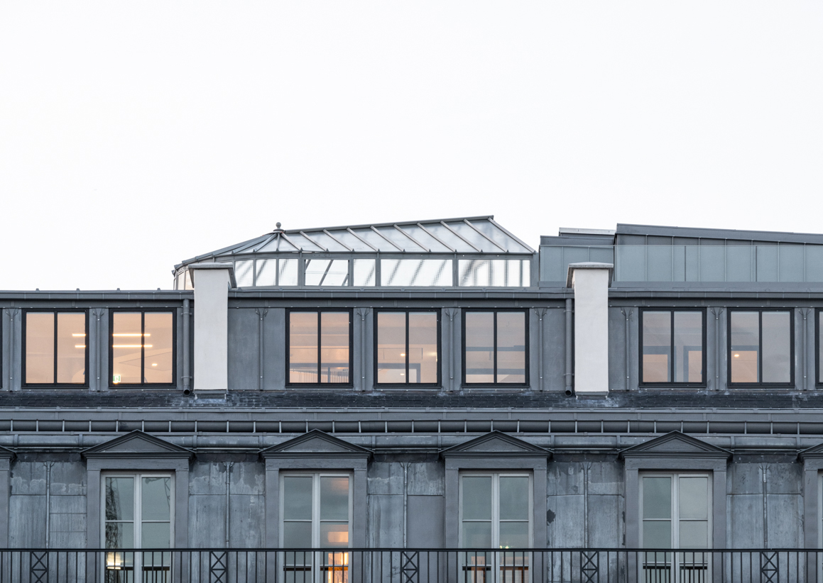 Verrière apparente sur le rooftop avec toitures en zinc parisiennes d'un immeuble de bureaux.