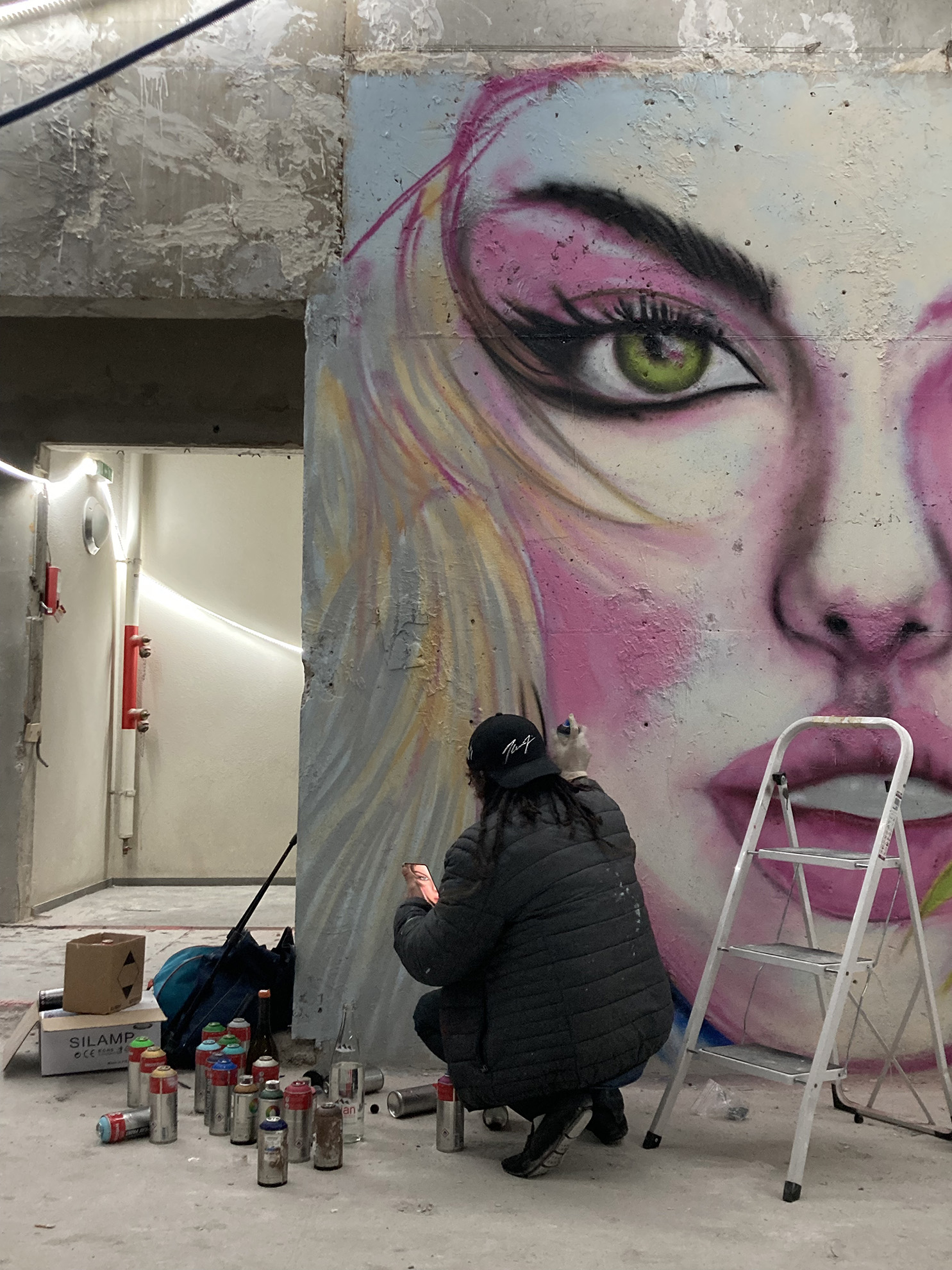 Une personne fait un graffiti du visage d'une femme sur le mur intérieur d'un immeuble en chantier
