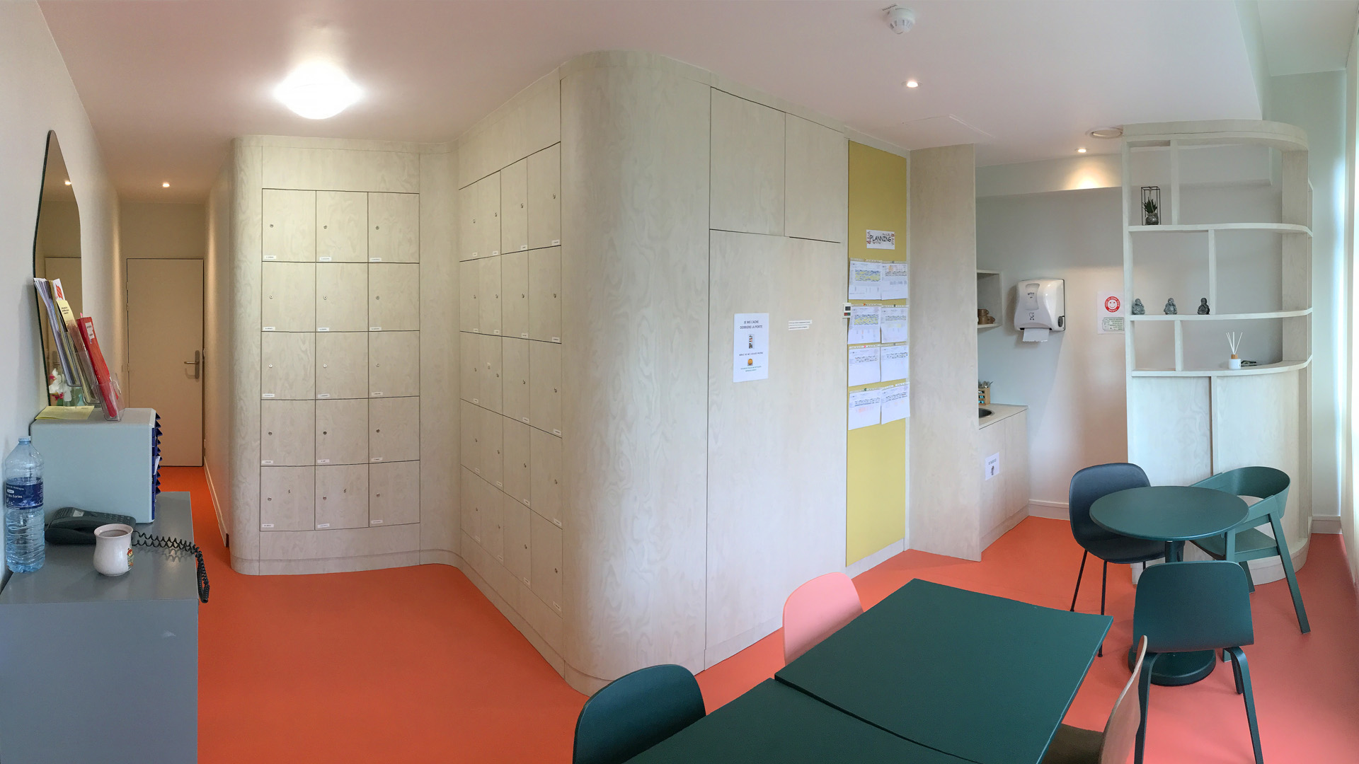 Salle de pause rénovée du personnel soignant d'un hôpital dans les tons beige, sol rosé et mobilier vert sapin.