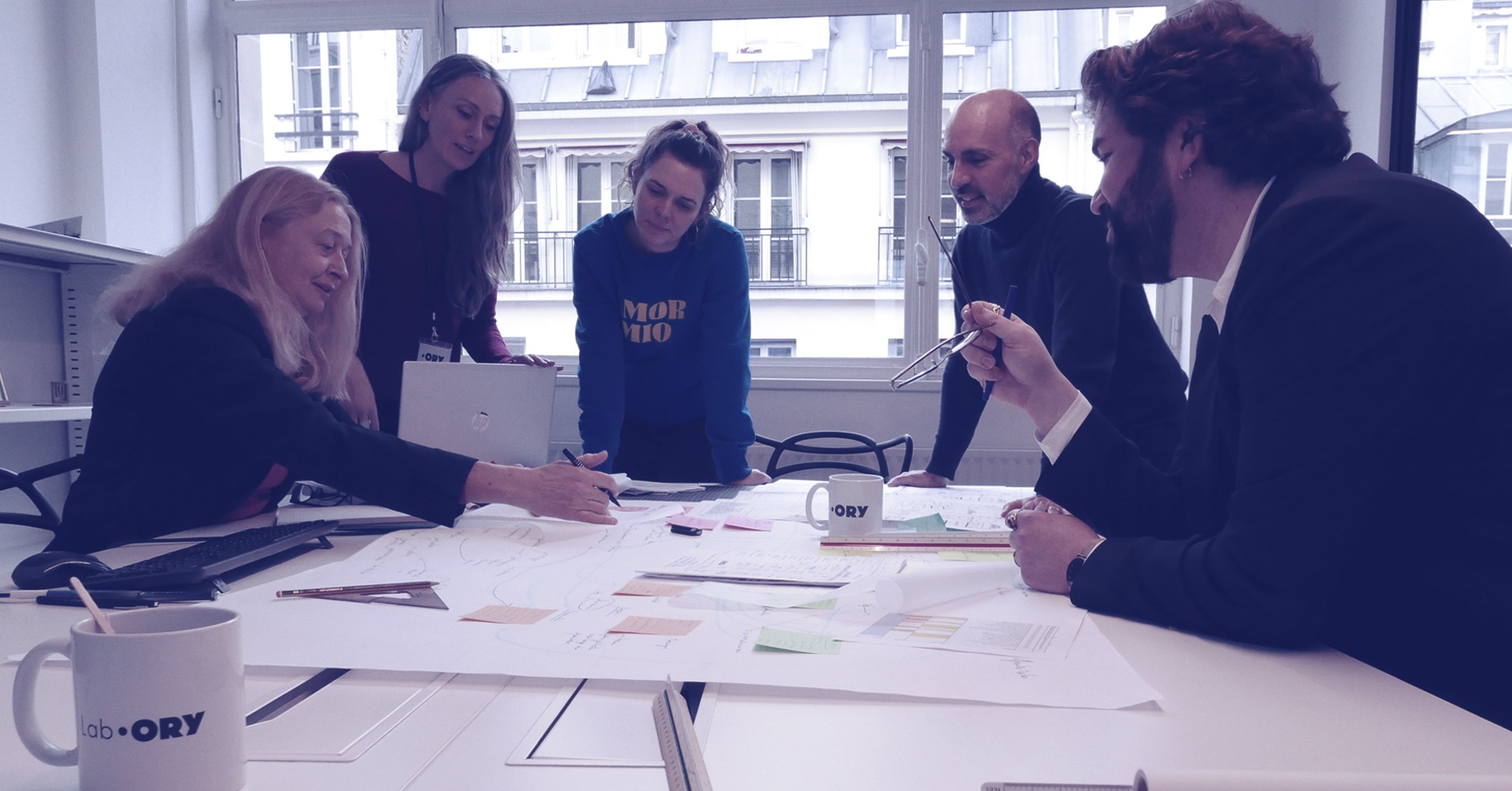 trois femmes et deux hommes autour d'une table de réunion regardent des plans