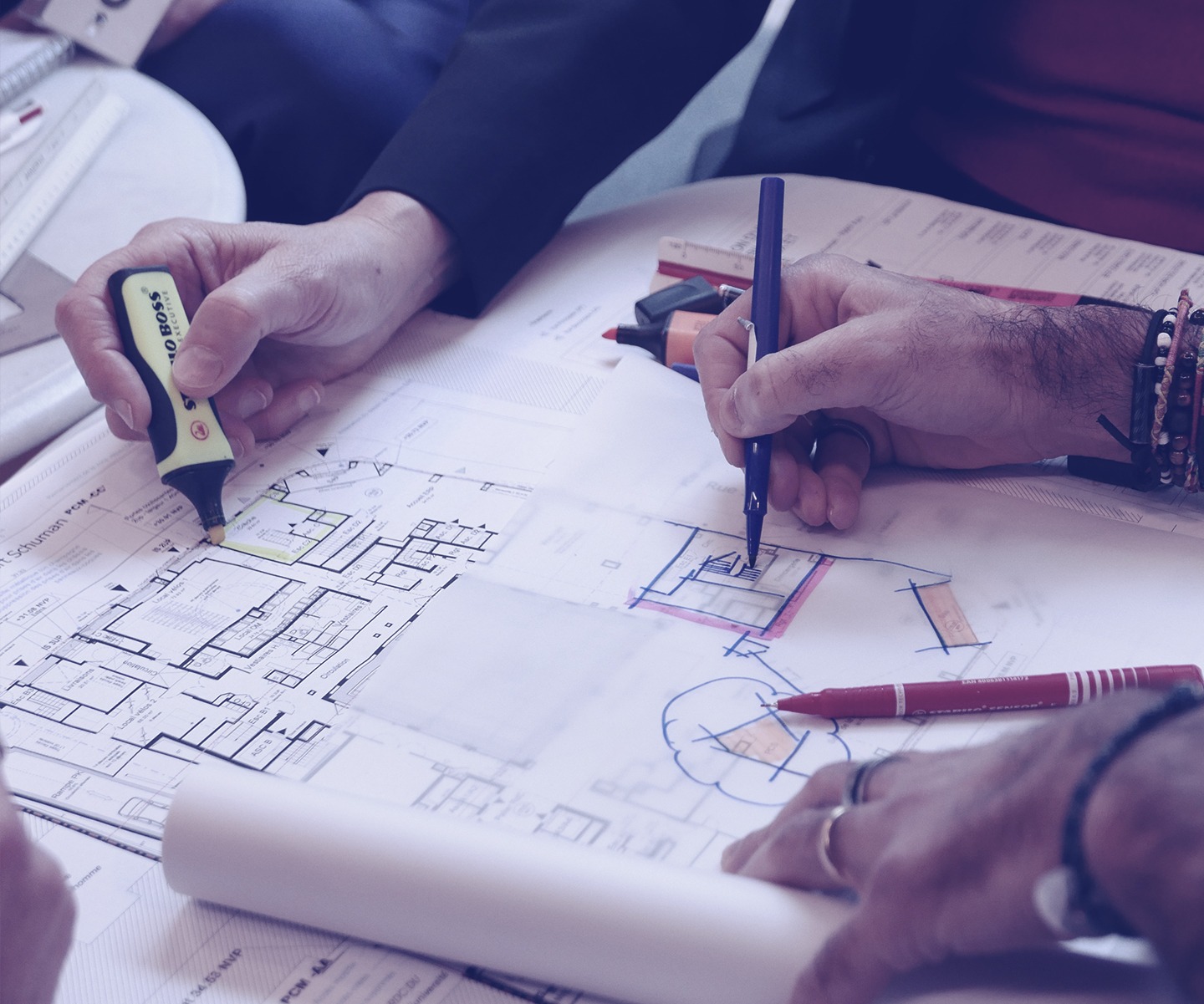 Les mains d'un homme et d'une femme tiennent des feutres et redessinent un plan d'architecture.